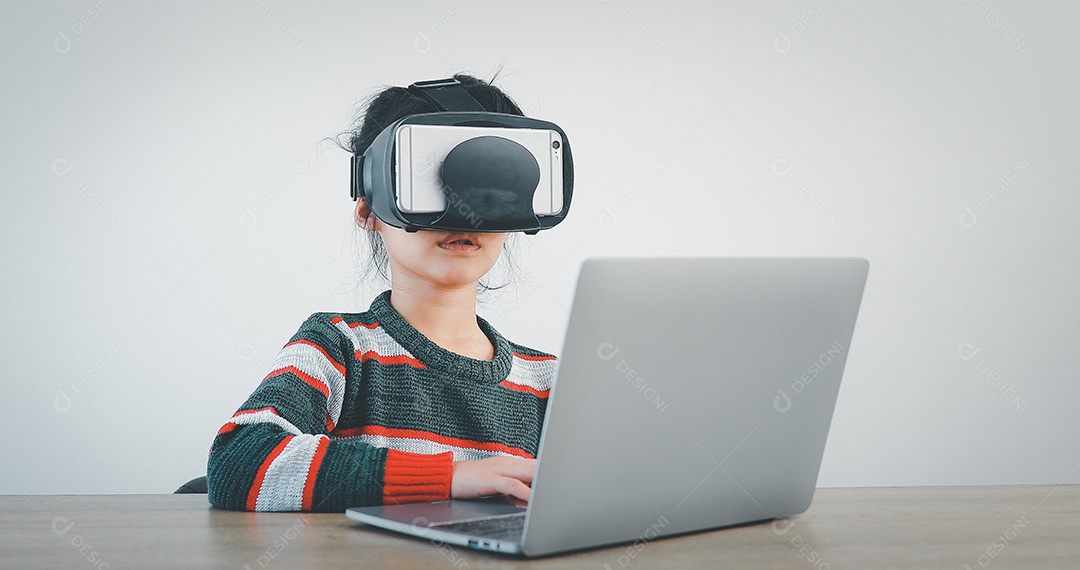 Linda menina criança usando oculos realidade virtual usando notebook
