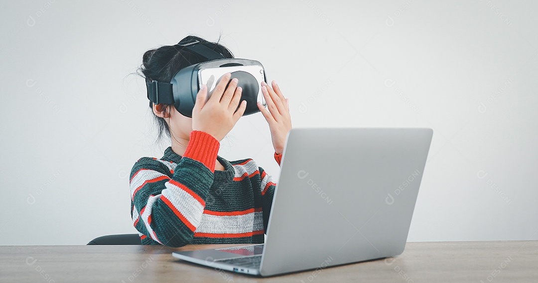 Linda menina criança usando oculos realidade virtual usando notebook