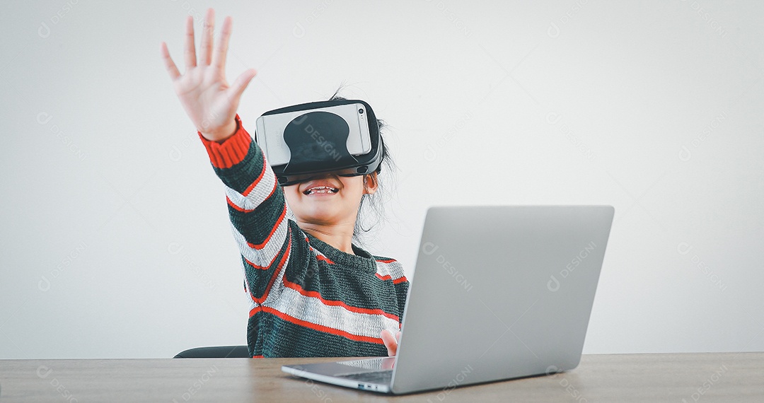 Linda menina criança usando oculos realidade virtual usando notebook