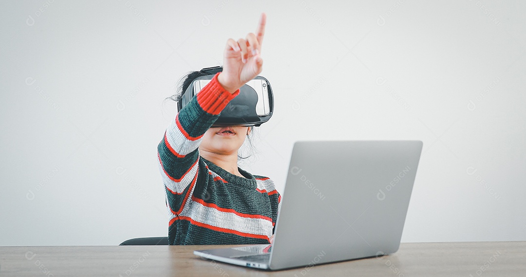 Linda menina criança usando oculos realidade virtual usando notebook