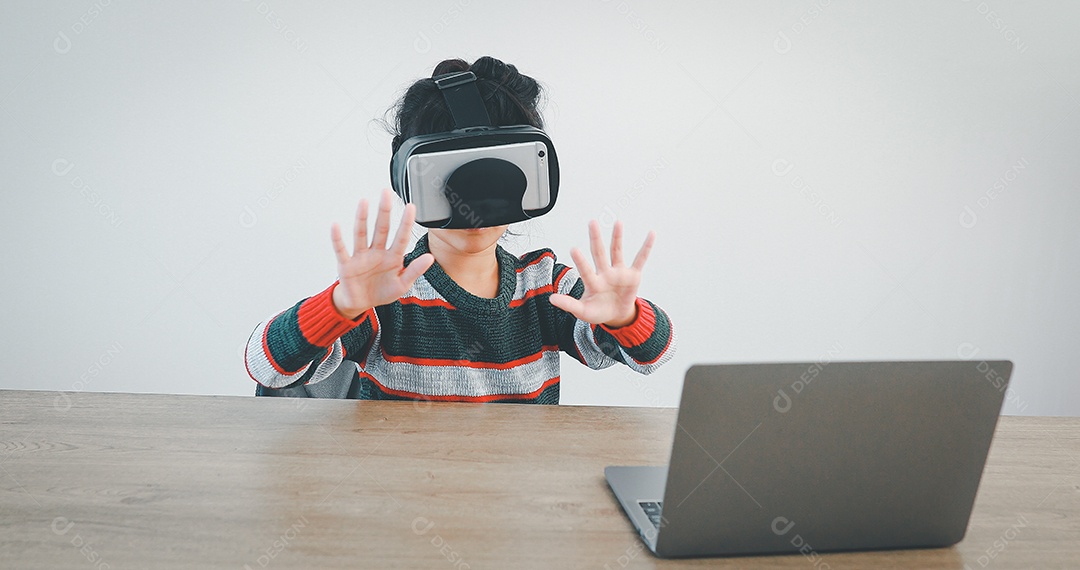 Linda menina criança usando oculos realidade virtual usando notebook
