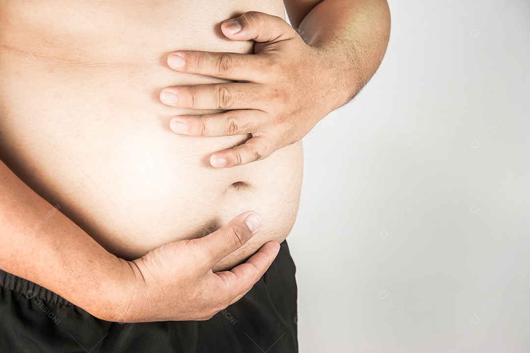 Corpo de homem com excesso de peso com as mãos tocando a gordura da barriga