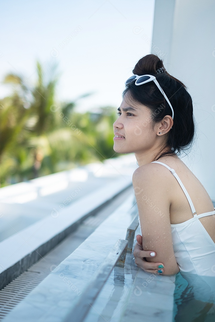 Mulher feliz em maiô branco nadando no hotel de luxo com piscina.