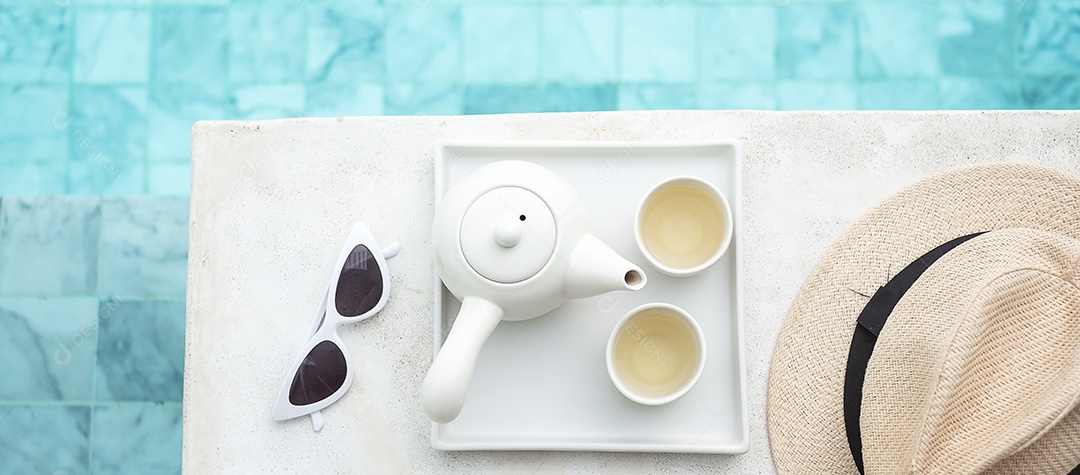 Óculos de sol brancos e bule de chá quente perto da piscina no hotel de luxo.