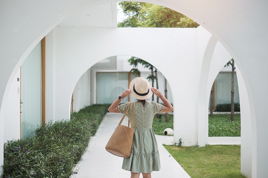 Feliz viajante mulher de vestido branco e chapéu desfruta no feriado.