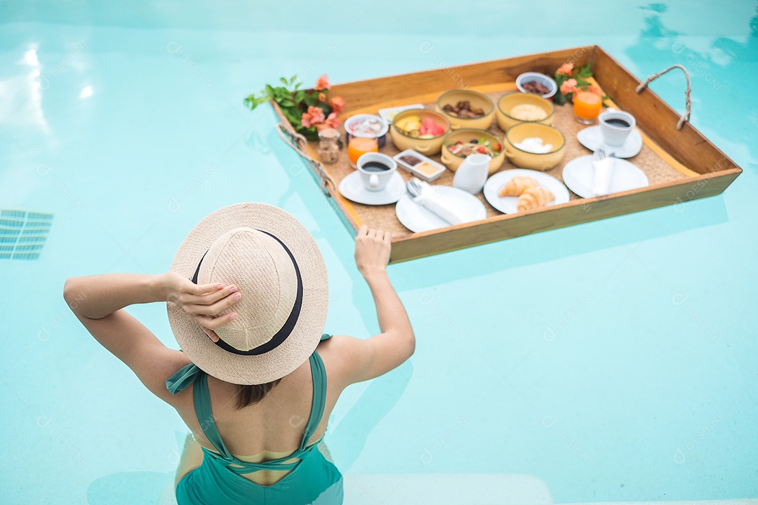 Mulher jovem feliz em traje de banho verde tomando café da manhã flutuante