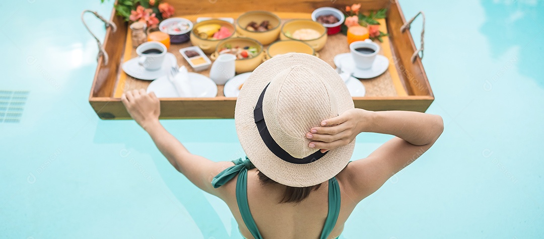 Mulher jovem feliz em traje de banho verde tomando café da manhã flutuante