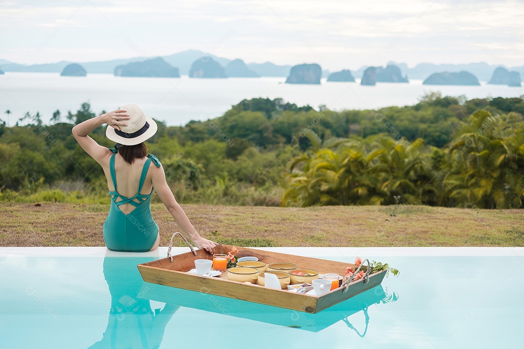 Mulher jovem feliz em traje de banho verde tomando café da manhã flutuante