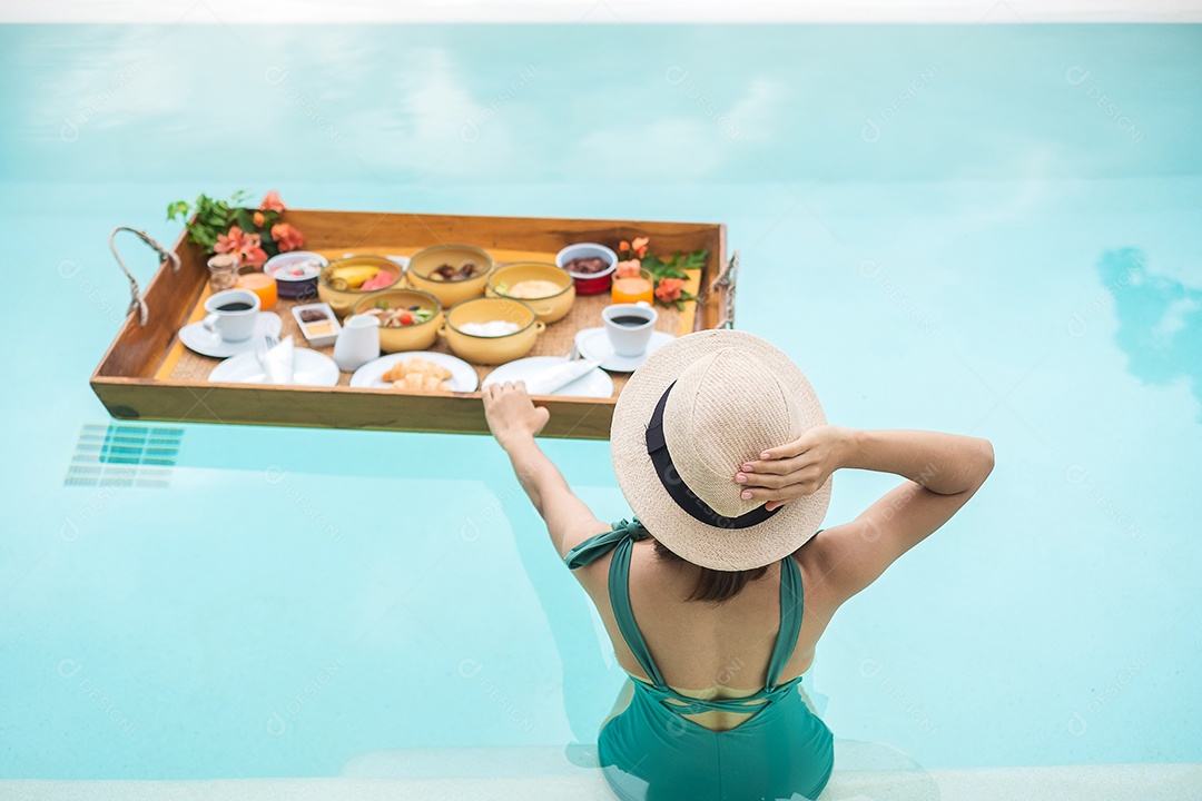 Mulher jovem feliz em traje de banho verde tomando café da manhã flutuante