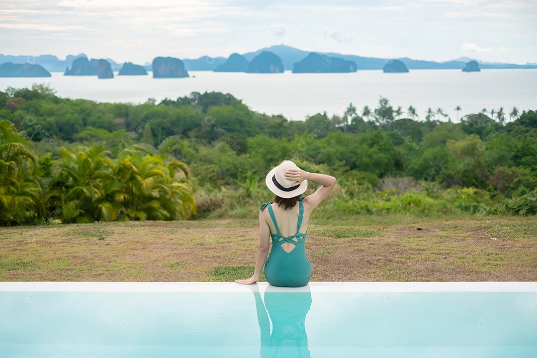 Mulher feliz em maiô verde nadando na piscina de luxo hotel