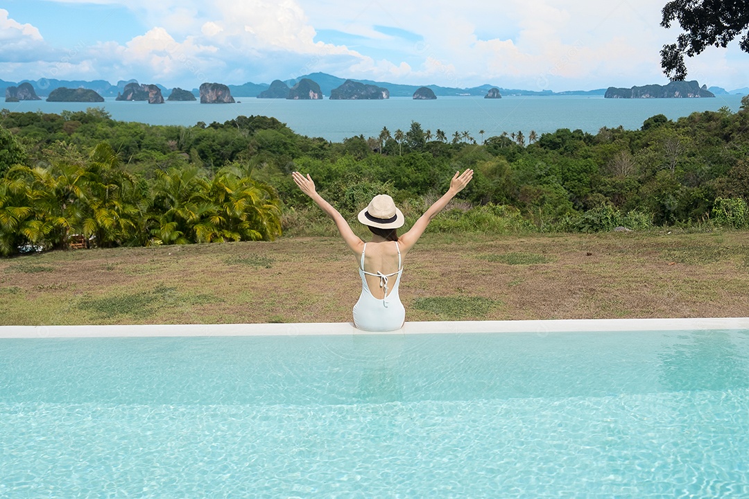 Mulher feliz em maiô branco nadando na piscina de luxo hotel