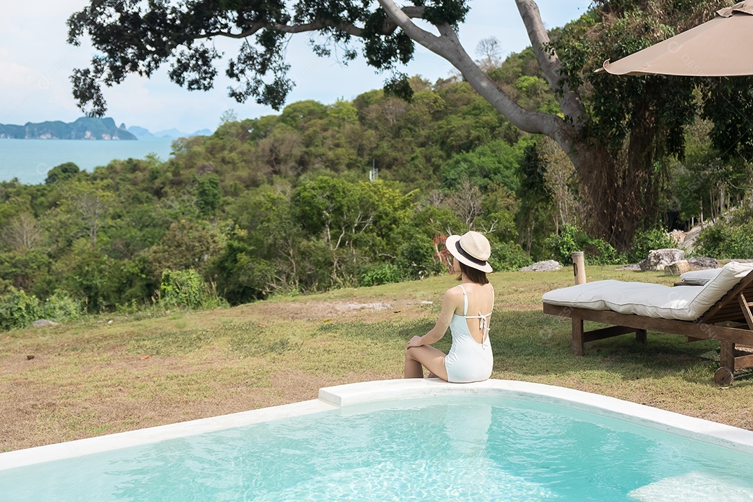 Happy woman in white swimsuit swimming in luxury hotel pool agai