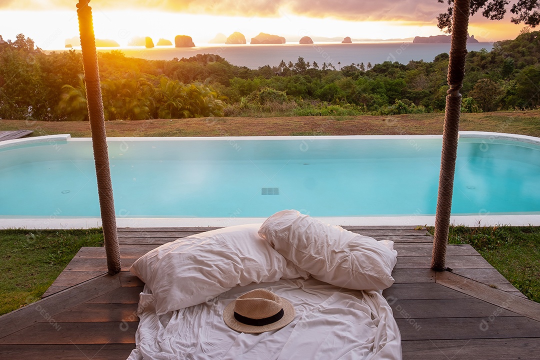 Chapéu de viajante na cama branca contra o fundo da bela vista para o mar