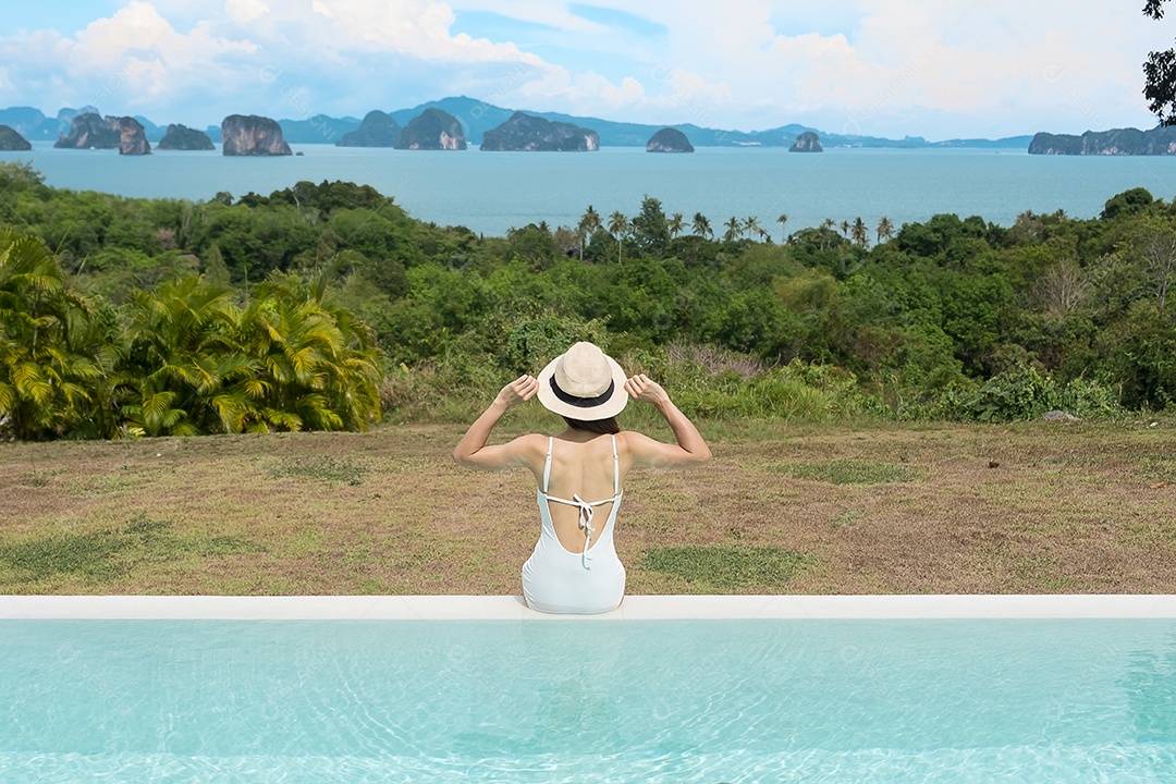 Mulher feliz em maiô branco nadando na piscina de luxo hotel