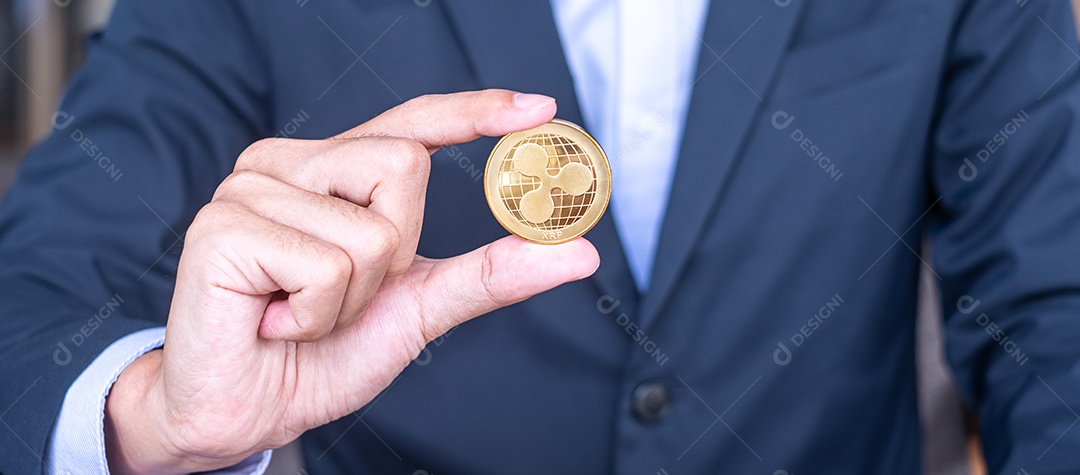 Mão de empresário segurando a moeda de criptomoeda Ripple dourada (XRP)