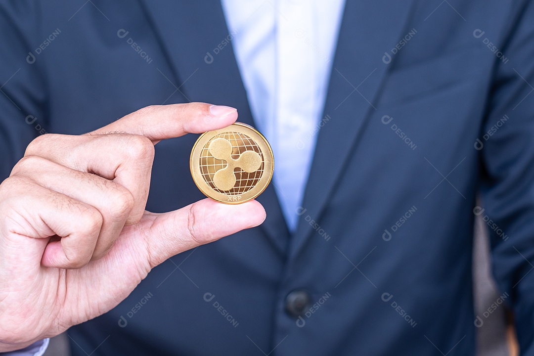 Mão de empresário segurando a moeda de criptomoeda Ripple dourada (XRP)