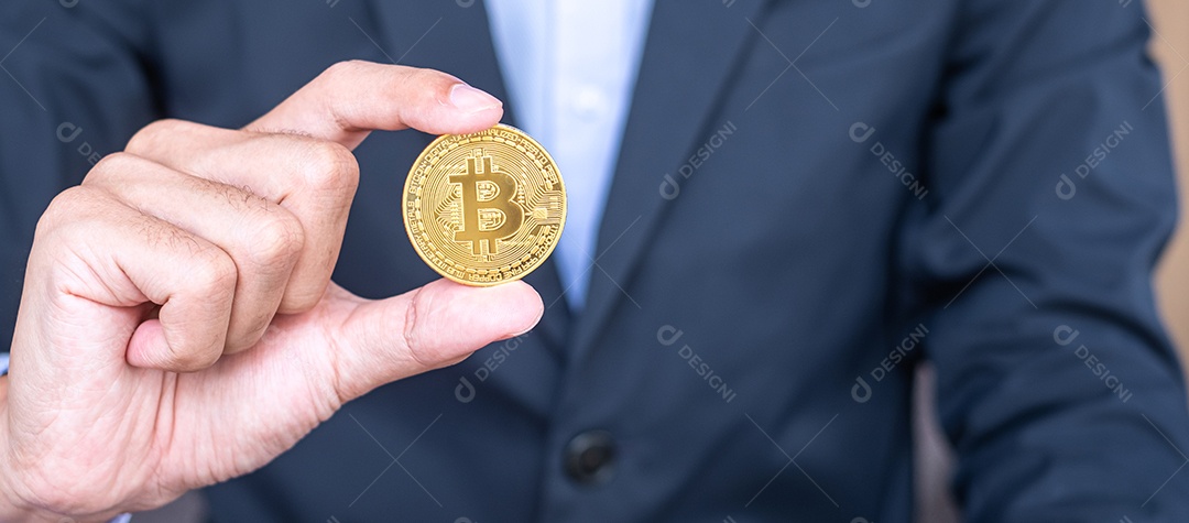 Mão de empresário segurando a criptomoeda Bitcoin (BTC) dourada