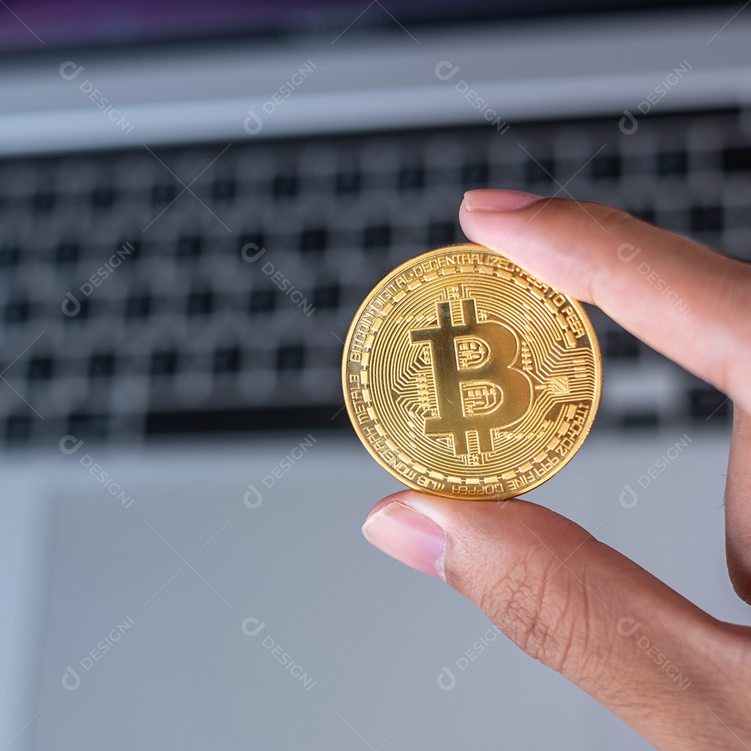 Mão de empresário segurando a criptomoeda Bitcoin (BTC) dourada
