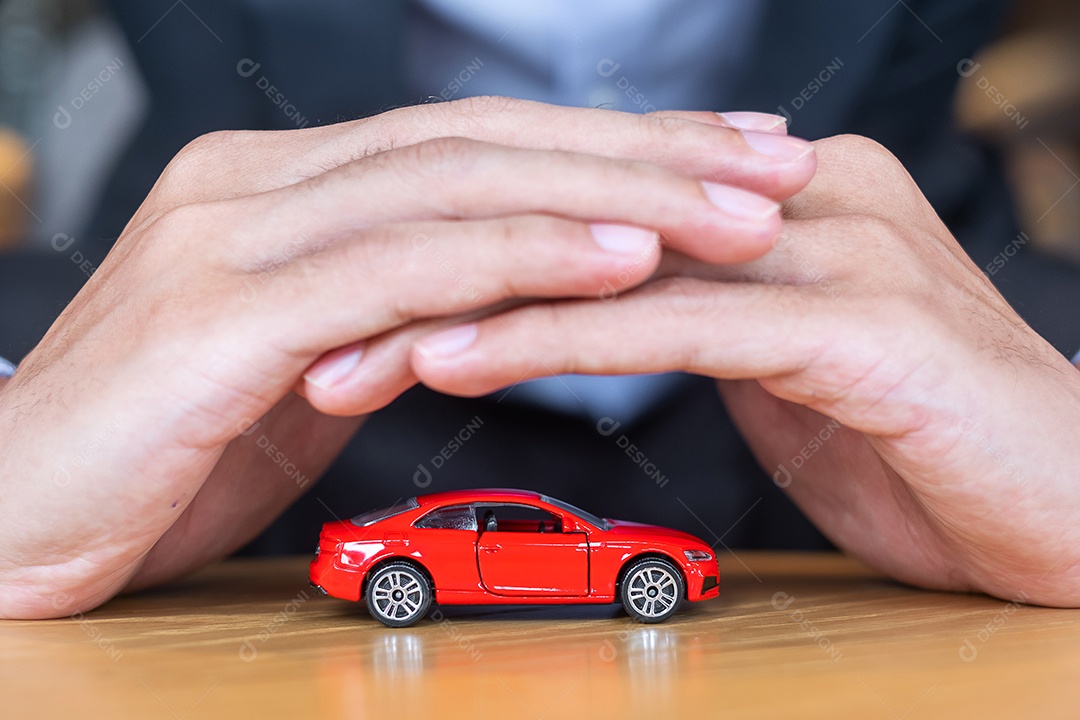 Capa de mão de empresário ou brinquedo de carro vermelho de proteção na mesa.