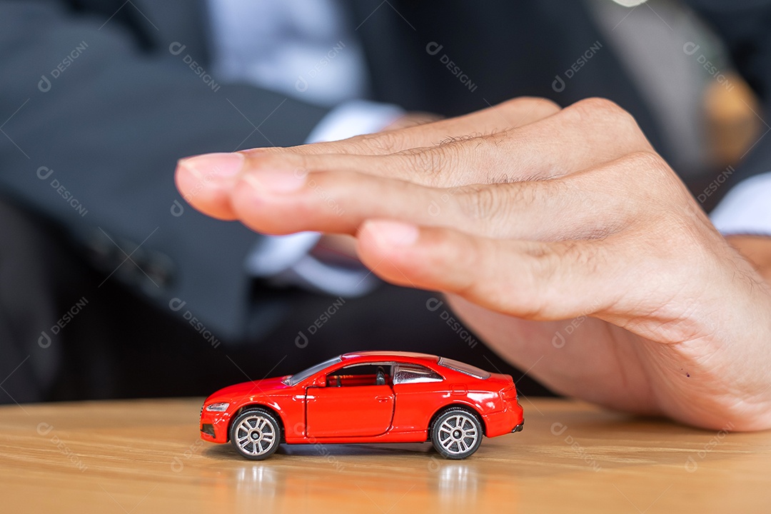 Capa de mão de empresário ou brinquedo de carro vermelho de proteção na mesa.