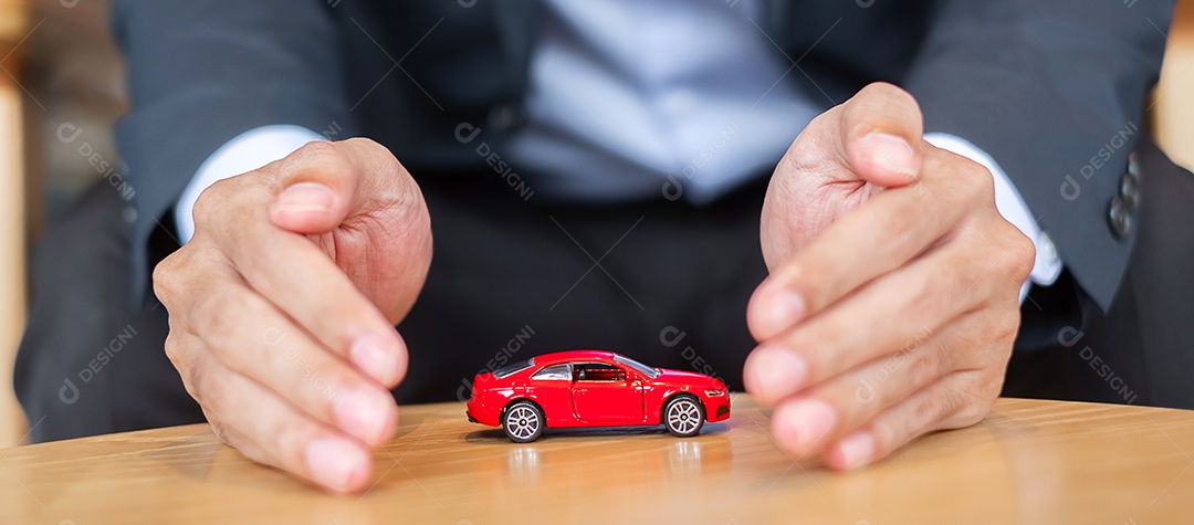 Capa de mão de empresário ou brinquedo de carro vermelho de proteção na mesa.
