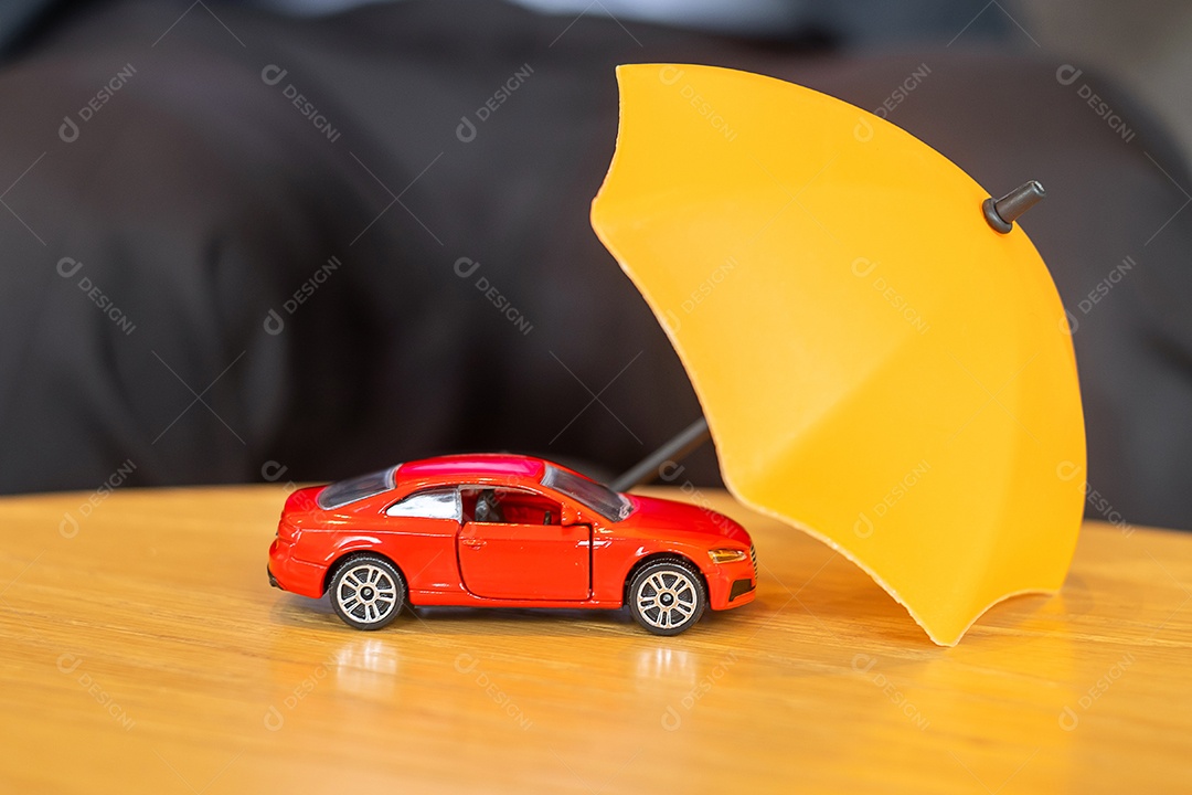 Capa de guarda-chuva amarela ou brinquedo de carro vermelho de proteção na mesa. Finanças