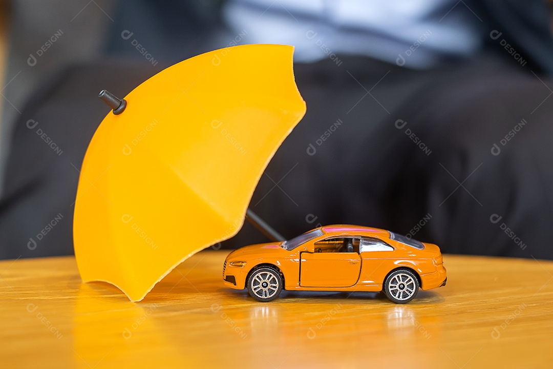 Capa de guarda-chuva amarela ou brinquedo de carro vermelho de proteção na mesa. Finanças