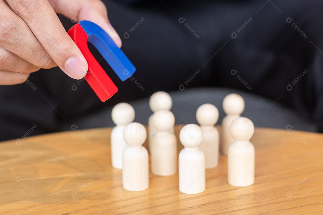 Mão de empresário segurando o ímã e puxando a figura de madeira do homem