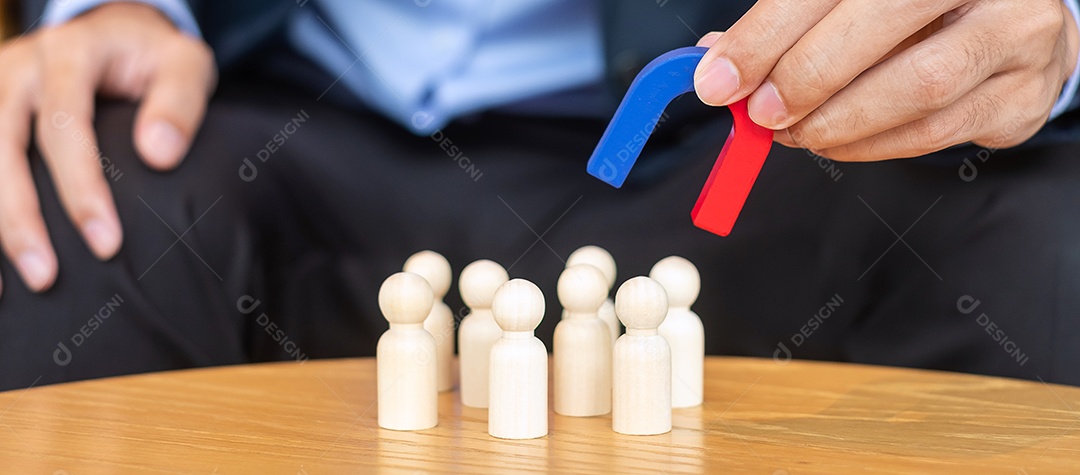 Mão de empresário segurando o ímã e puxando a figura de madeira do homem