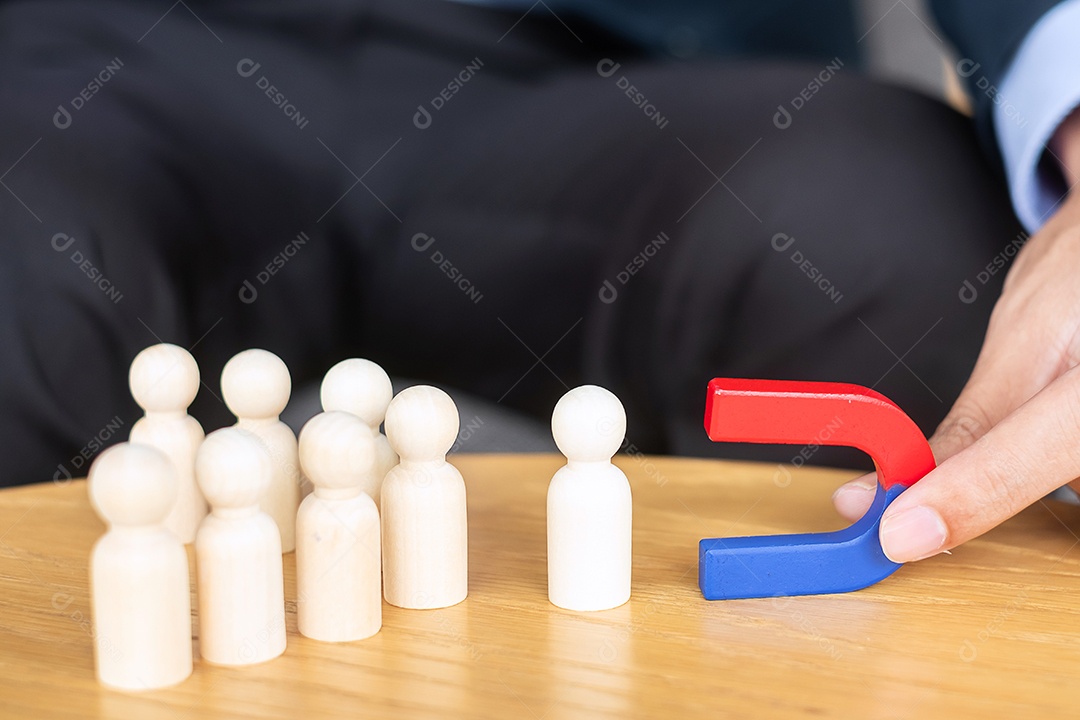 Mão de empresário segurando o ímã e puxando a figura de madeira do homem