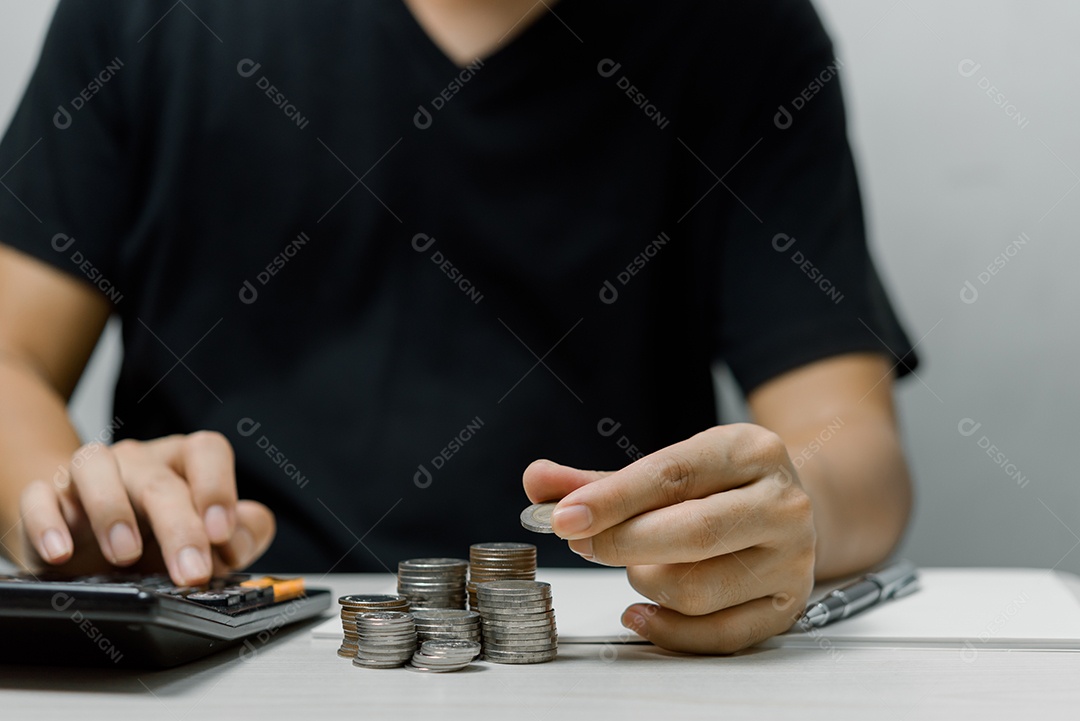 Empresário coloca dinheiro de pilha de moedas e muitas notas de banco no escritório.