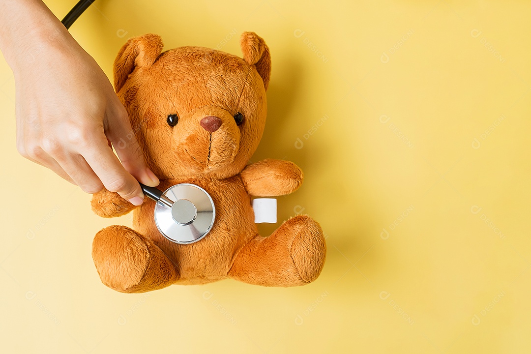 mão segurando estetoscópio na boneca Urso para apoiar a vida da criança