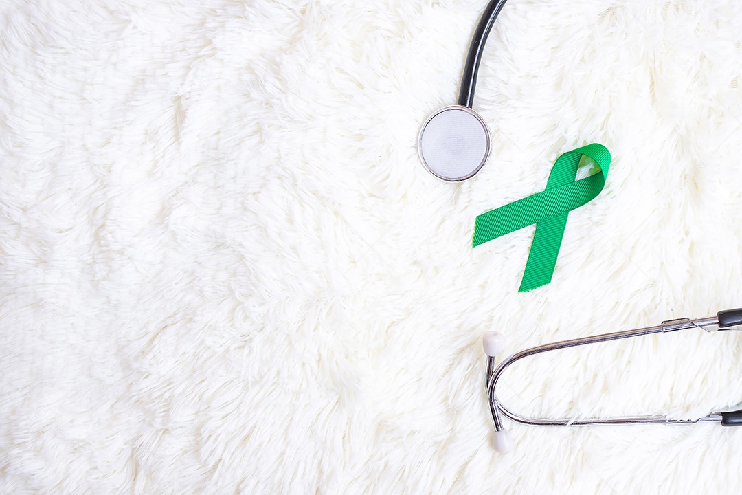 Mão segurando a fita verde para apoiar as pessoas que vivem e doentes