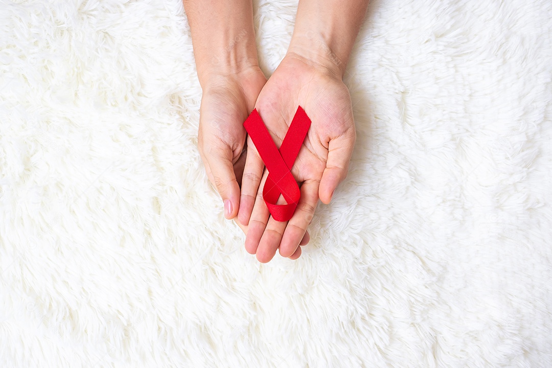 Mão segurando a fita vermelha para apoiar as pessoas que vivem e doenças