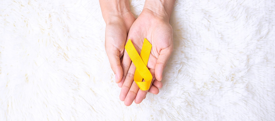 hand holding yellow ribbon on white background to support suicide prevention