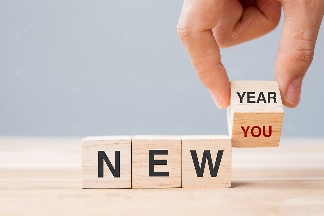 Mão flip bloco de madeira com texto de Ano Novo para Novo Você na mesa.