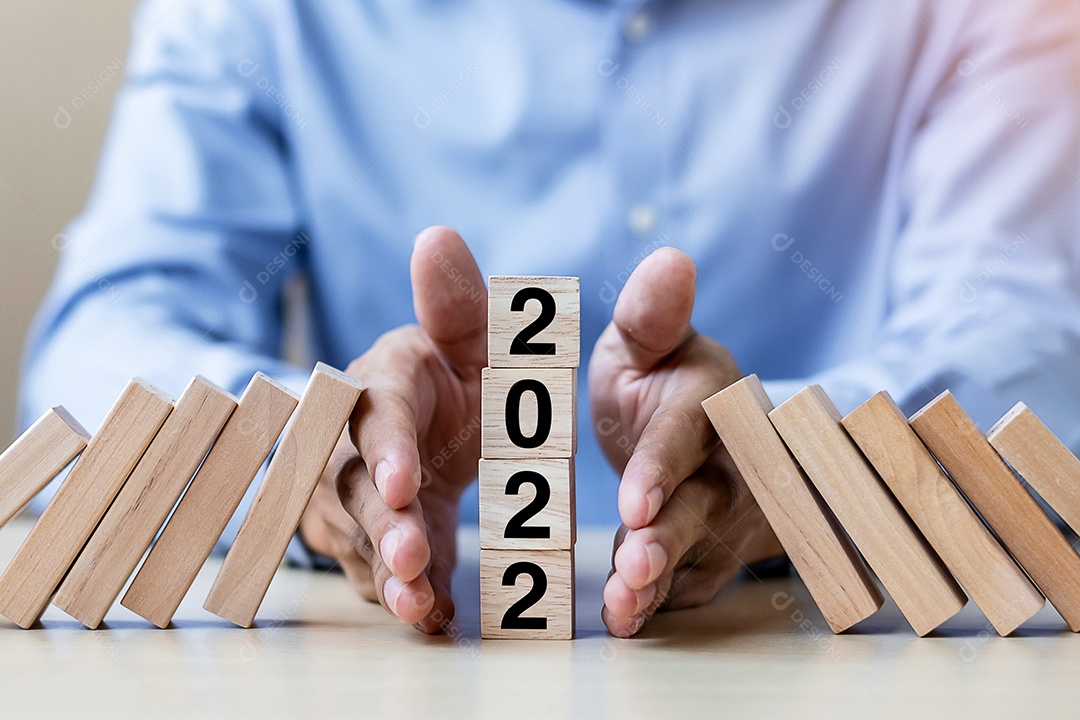 Mão de empresário parando de cair de 2022 blocos de madeira.