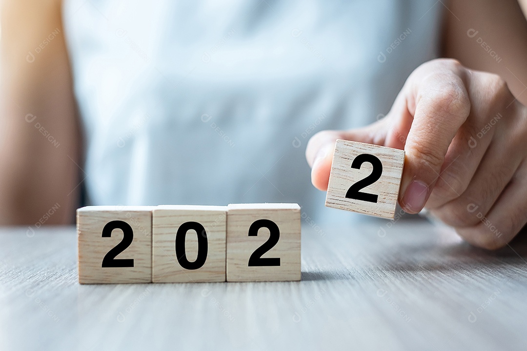 Mão de mulher de negócios segurando um cubo de madeira com texto de 2022 no fundo da mesa. Resolução, estratégia, solução, objetivo, negócios, ano novo você e conceitos de boas festas