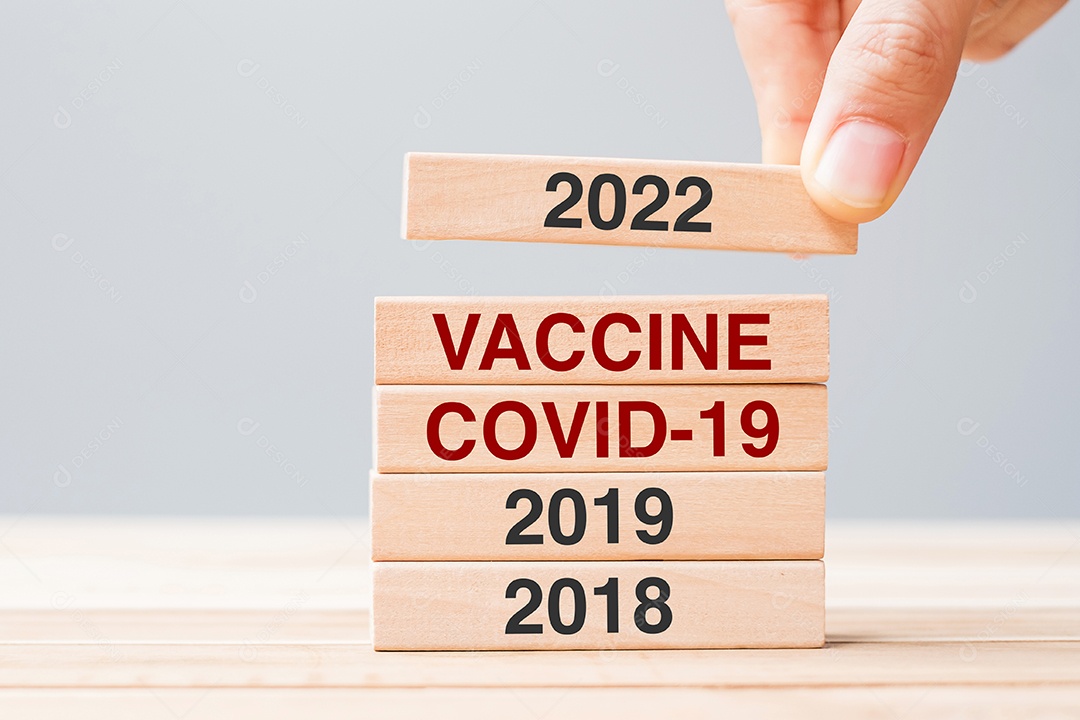 mão puxando o bloco de 2022 sobre Vacina, COVID-19 e 2019 blocos de madeira
