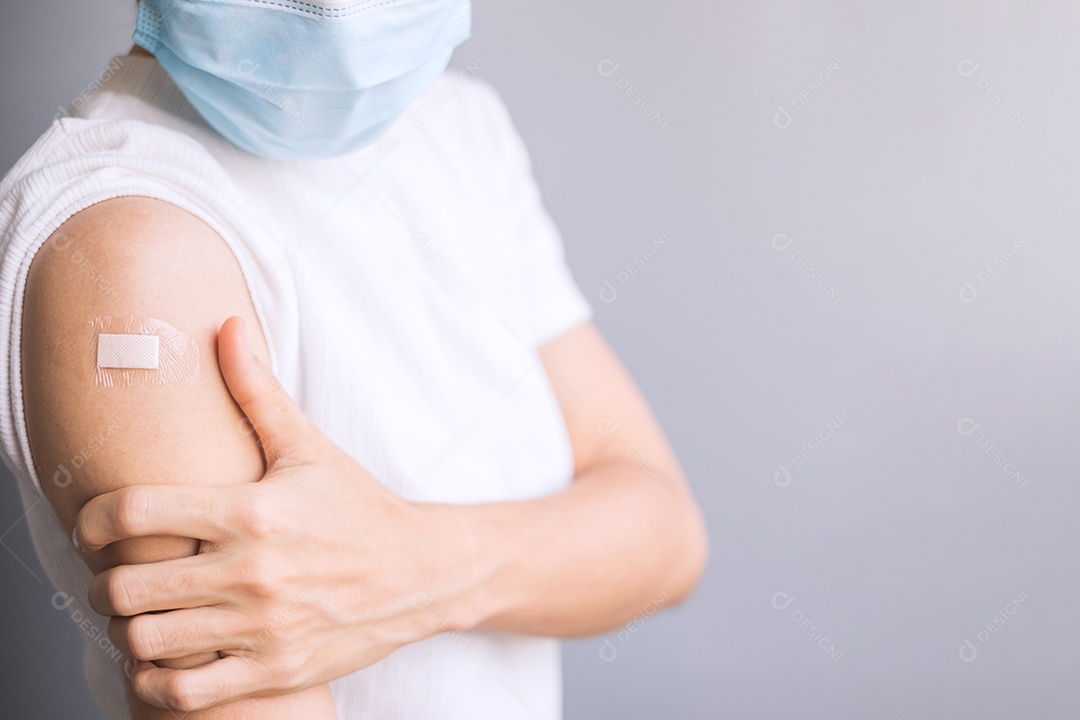 Mulher feliz mostrando o braço com curativo após receber a vacina