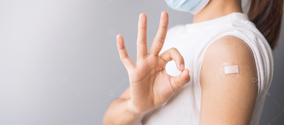 Mulher feliz mostrando o braço com curativo e dando sinal de mão ok