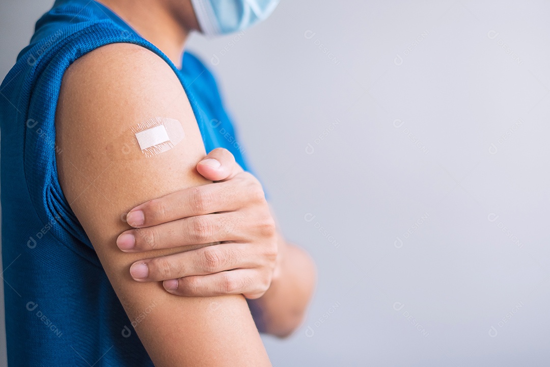 Homem feliz mostrando o braço com curativo após receber a vacina.
