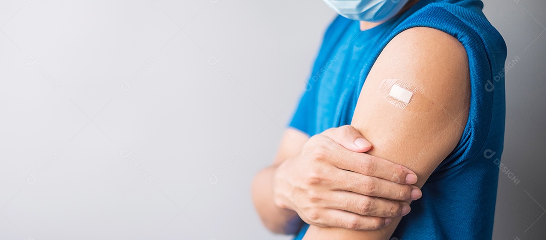 Homem feliz mostrando o braço com curativo depois de receber a vacina.