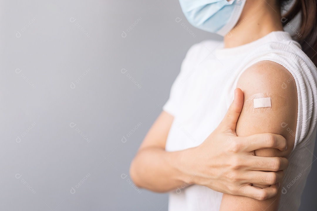 Mulher feliz mostrando o braço com curativo após receber a vacina