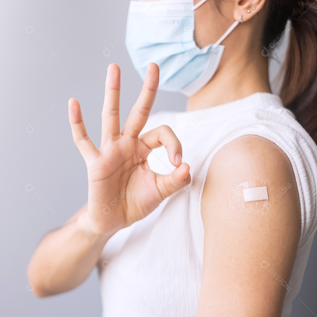 Mulher feliz mostrando o braço com curativo após receber a vacina