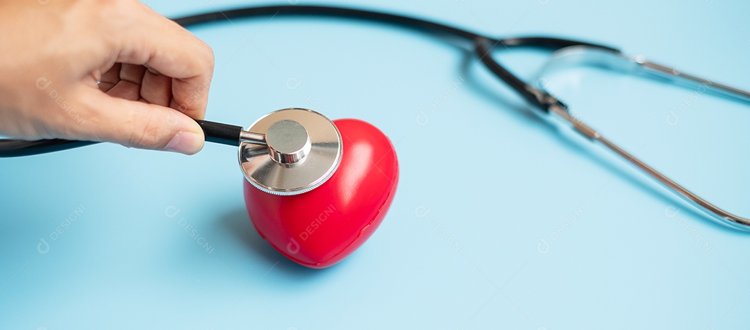 Mão de médico segurando estetoscópio com forma de coração vermelho em azul