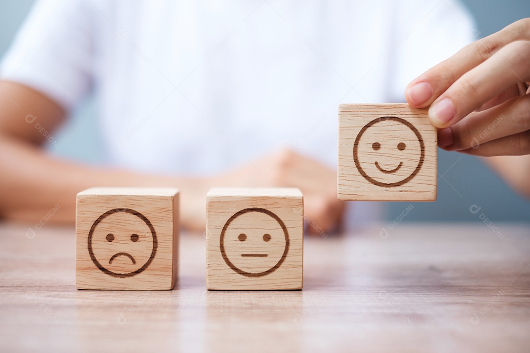 Mão de homem segurando o bloco de rosto de emoção. Cliente escolhe Emoticon