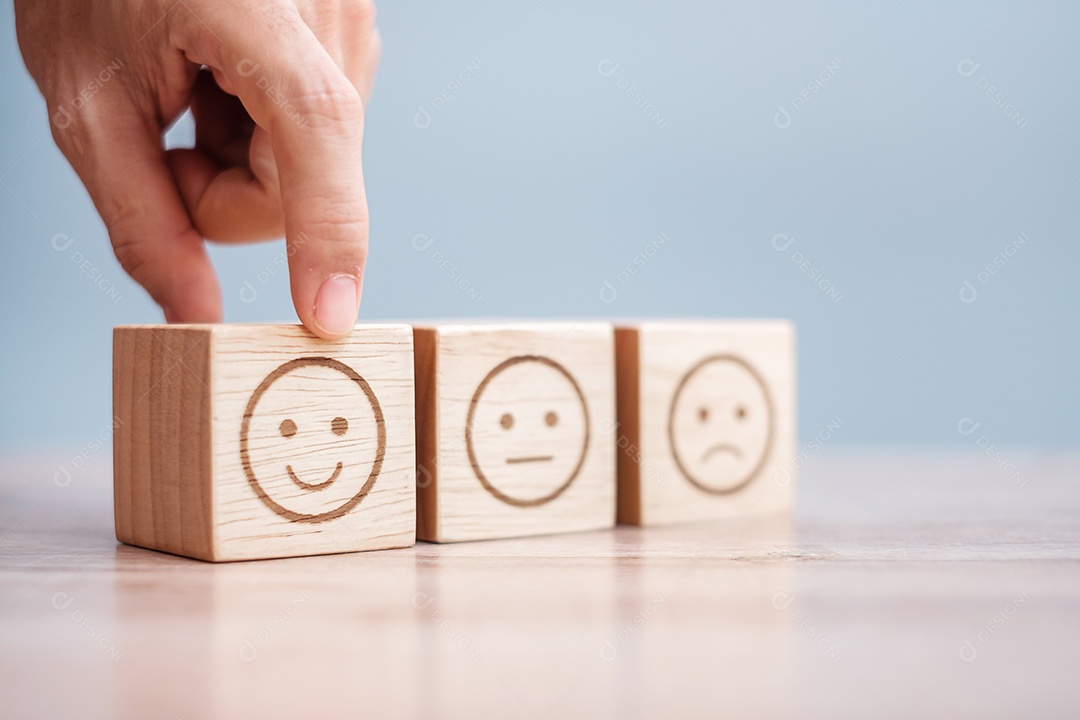 Mão de homem segurando o bloco de rosto de emoção. Cliente escolhe Emoticon