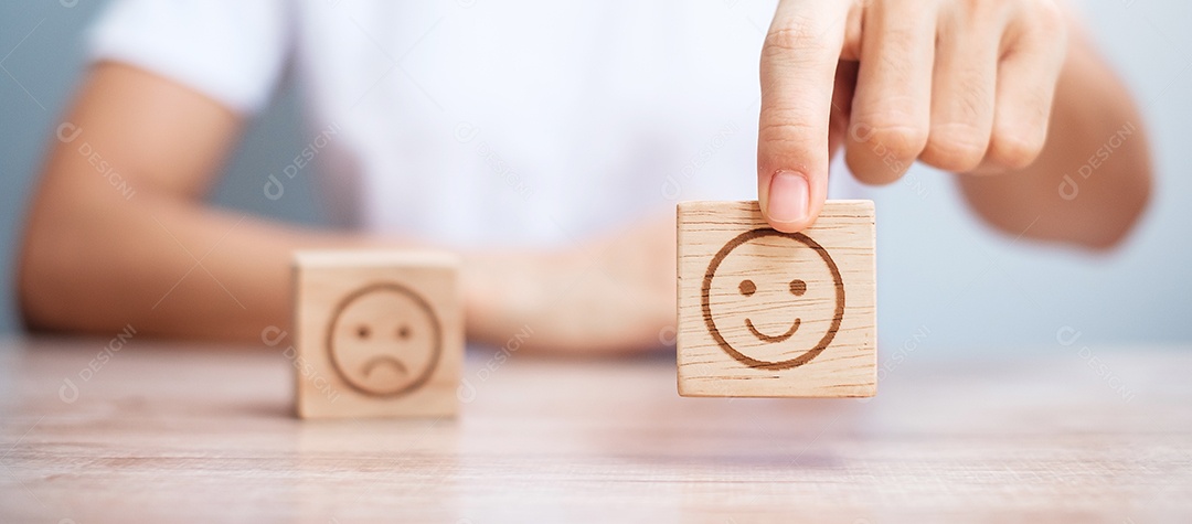 Mão de homem segurando o bloco de rosto de emoção. Cliente escolhe Emoticon