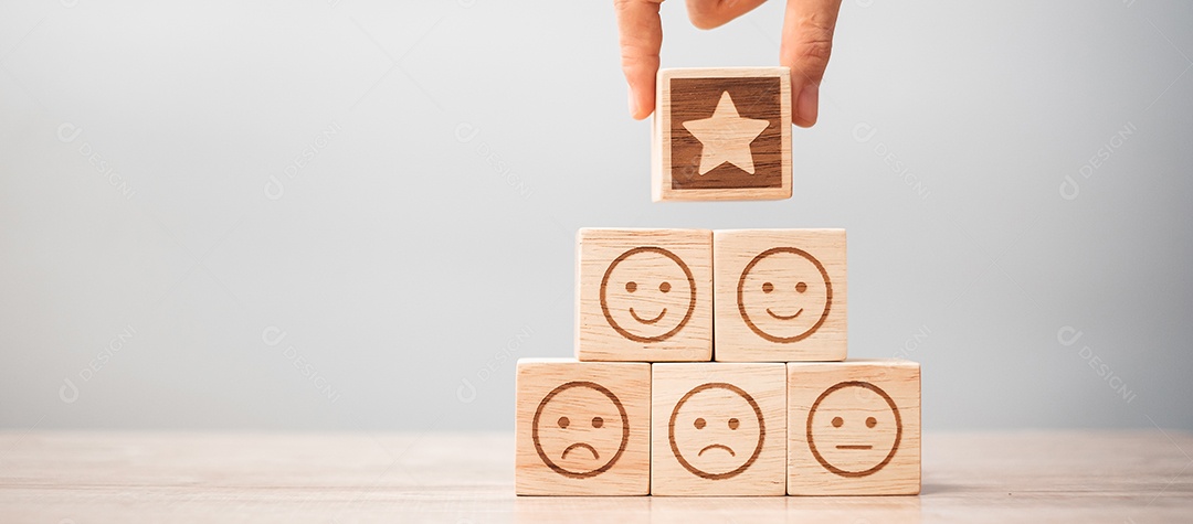 mão segurando a estrela sobre blocos de símbolo de rosto de emoção na mesa background